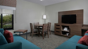 Una habitación de hotel con comedor, televisión y sofá.