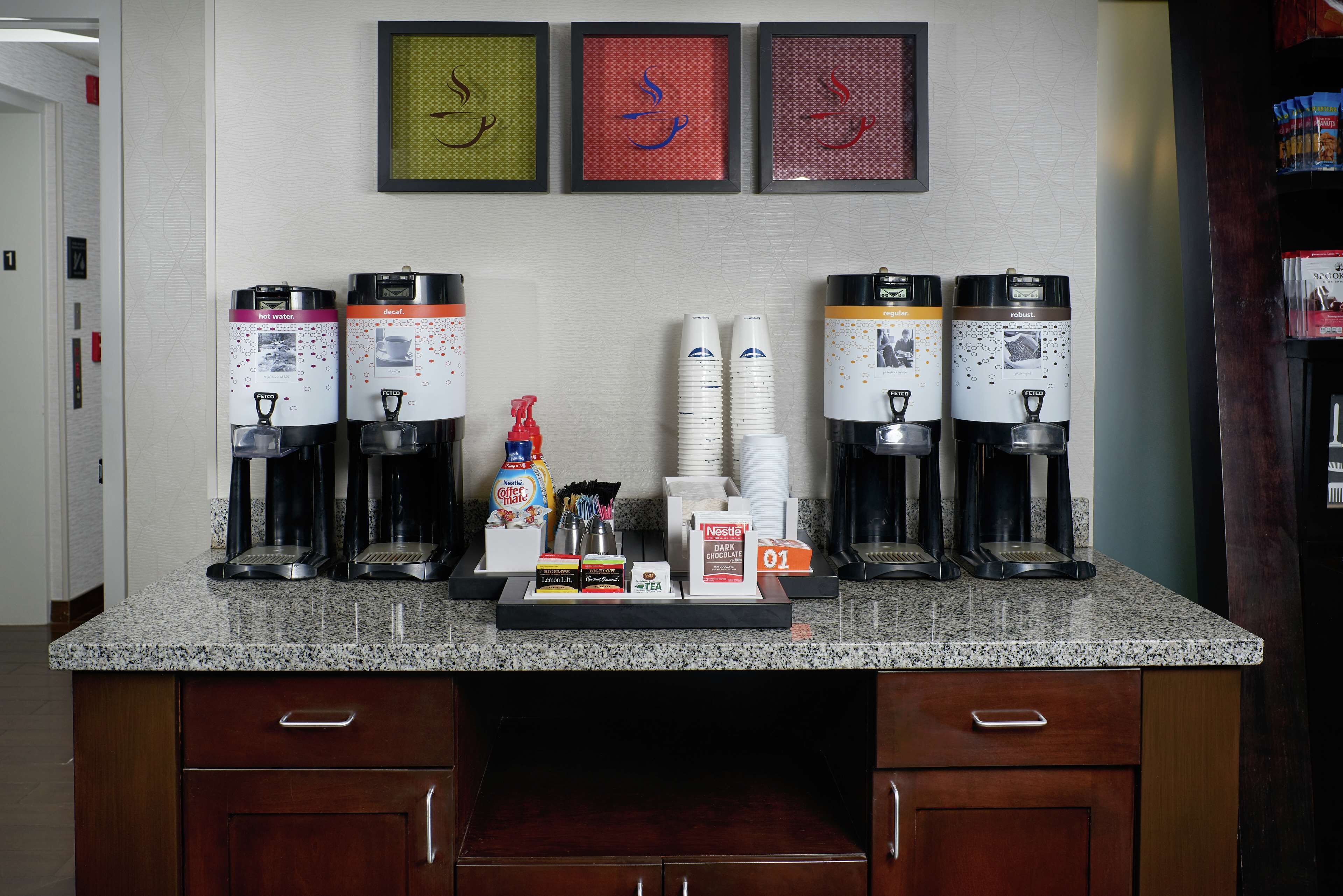 A kitchen area with coffee makers, hot water dispensers, and a coffee station.