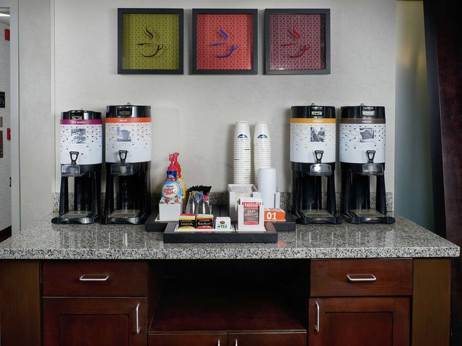 Un espacio tipo cocina con cafeteras, dispensadores de agua caliente y una estación de café.