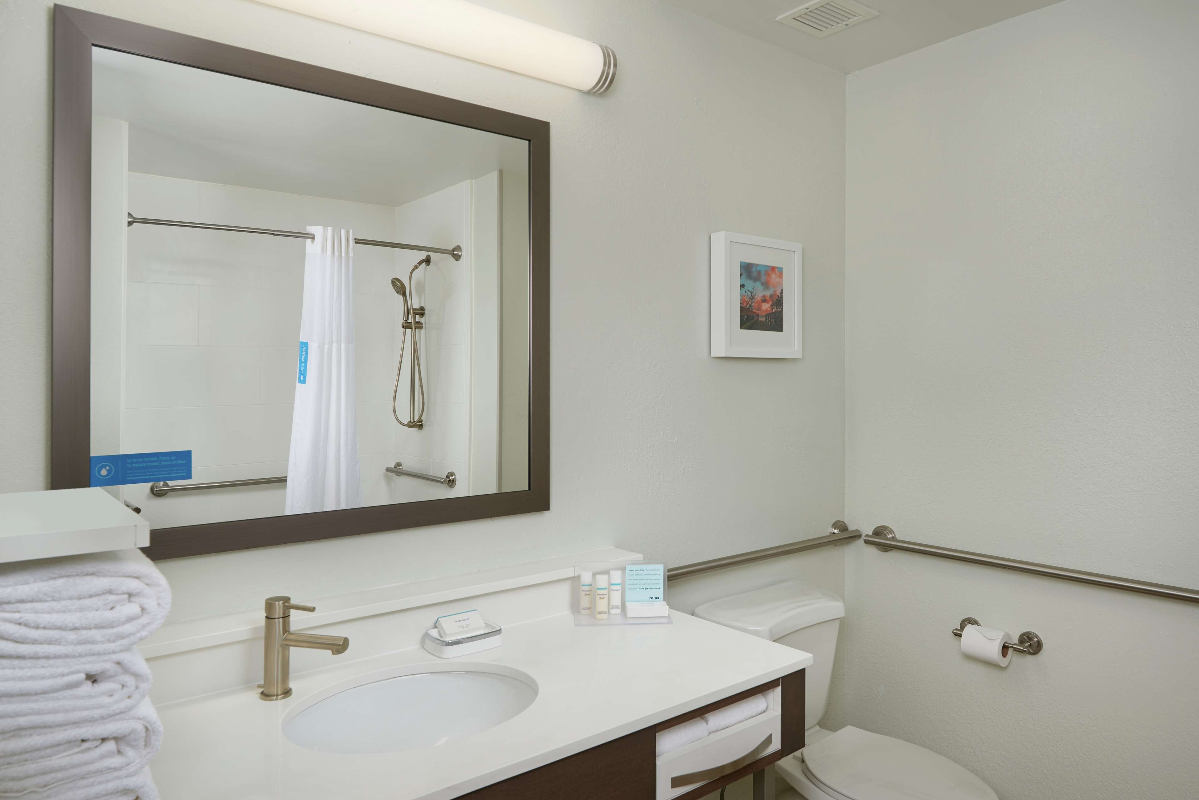 A bathroom with a sink, mirror, toilet, and shower.