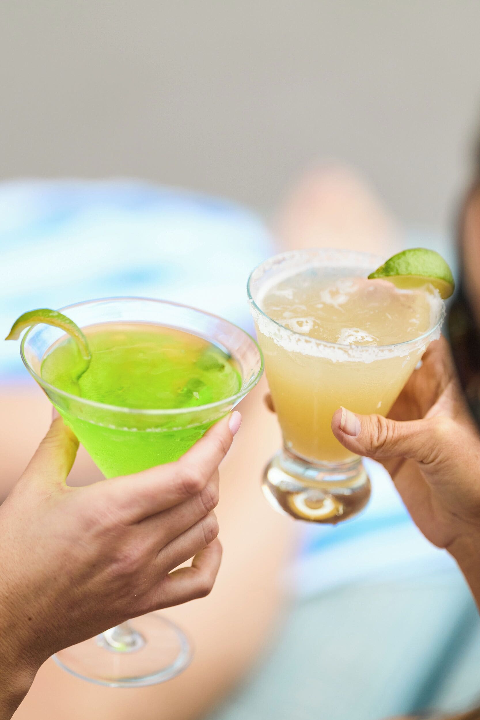 Deux personnes tenant des verres à cocktail décorés de quartiers de citron vert.