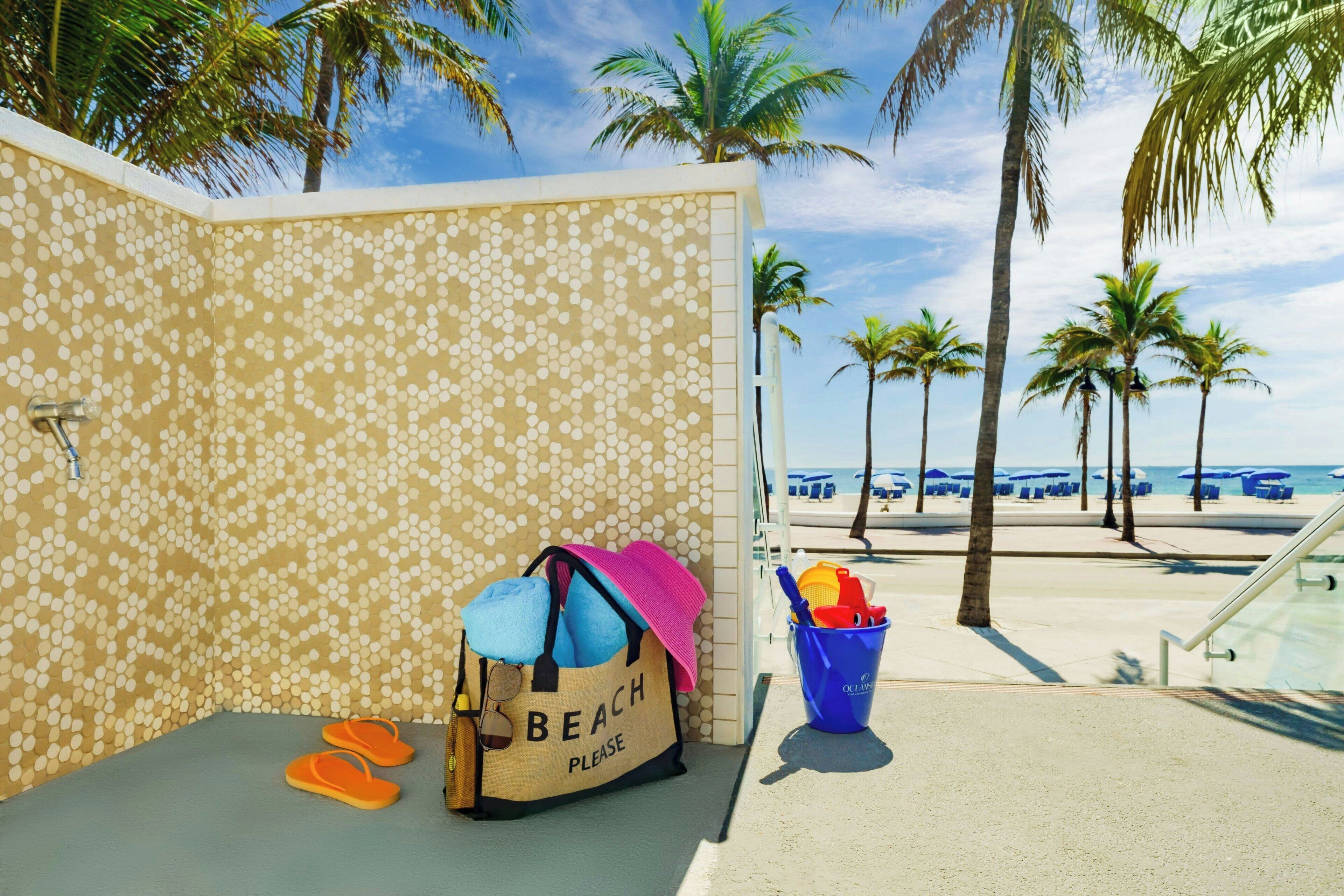 Una habitación junto a la playa con una pared a lunares, una bolsa de playa, chanclas y un cubo con juguetes de playa.