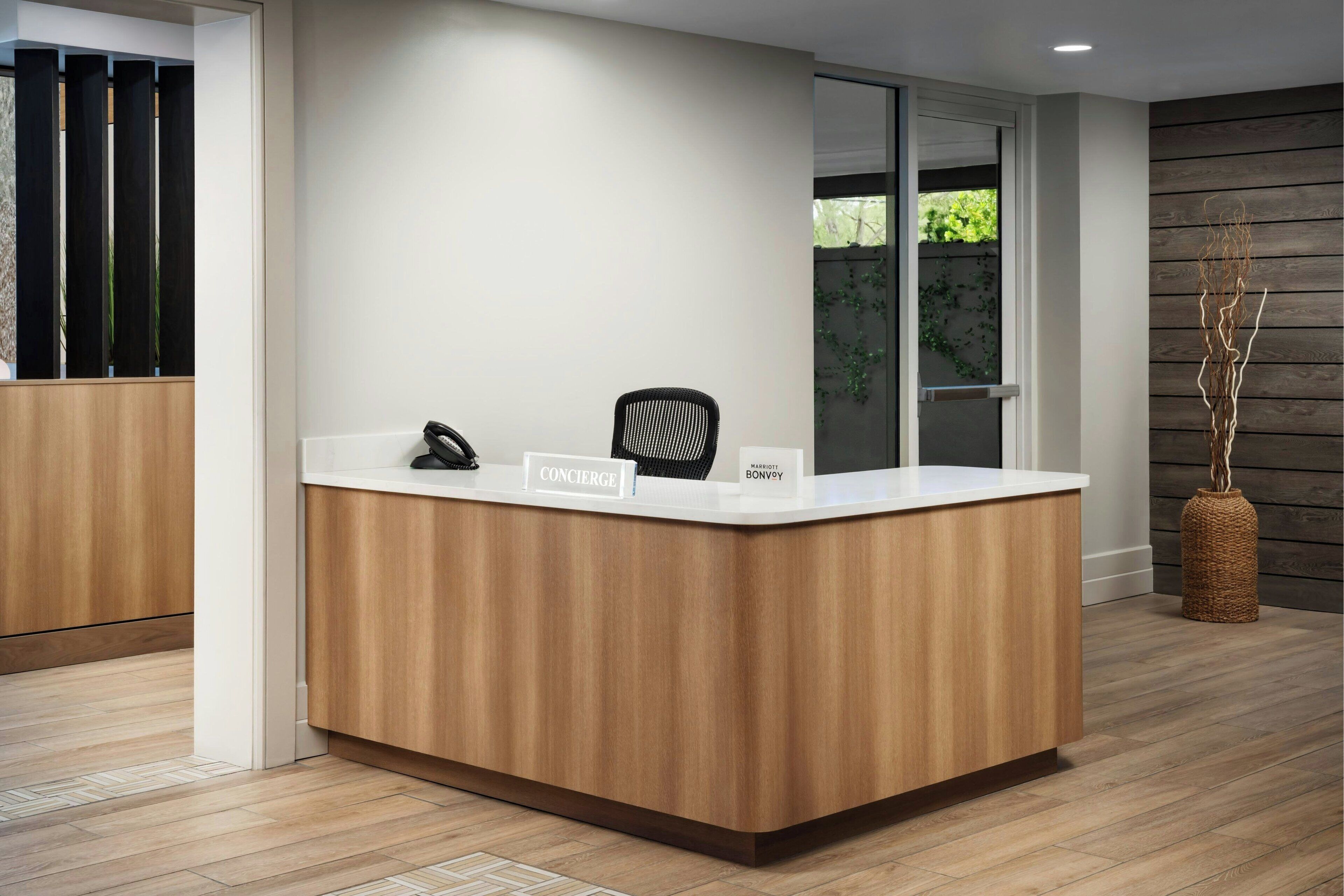 A reception desk with a nameplate, a telephone, and a chair.