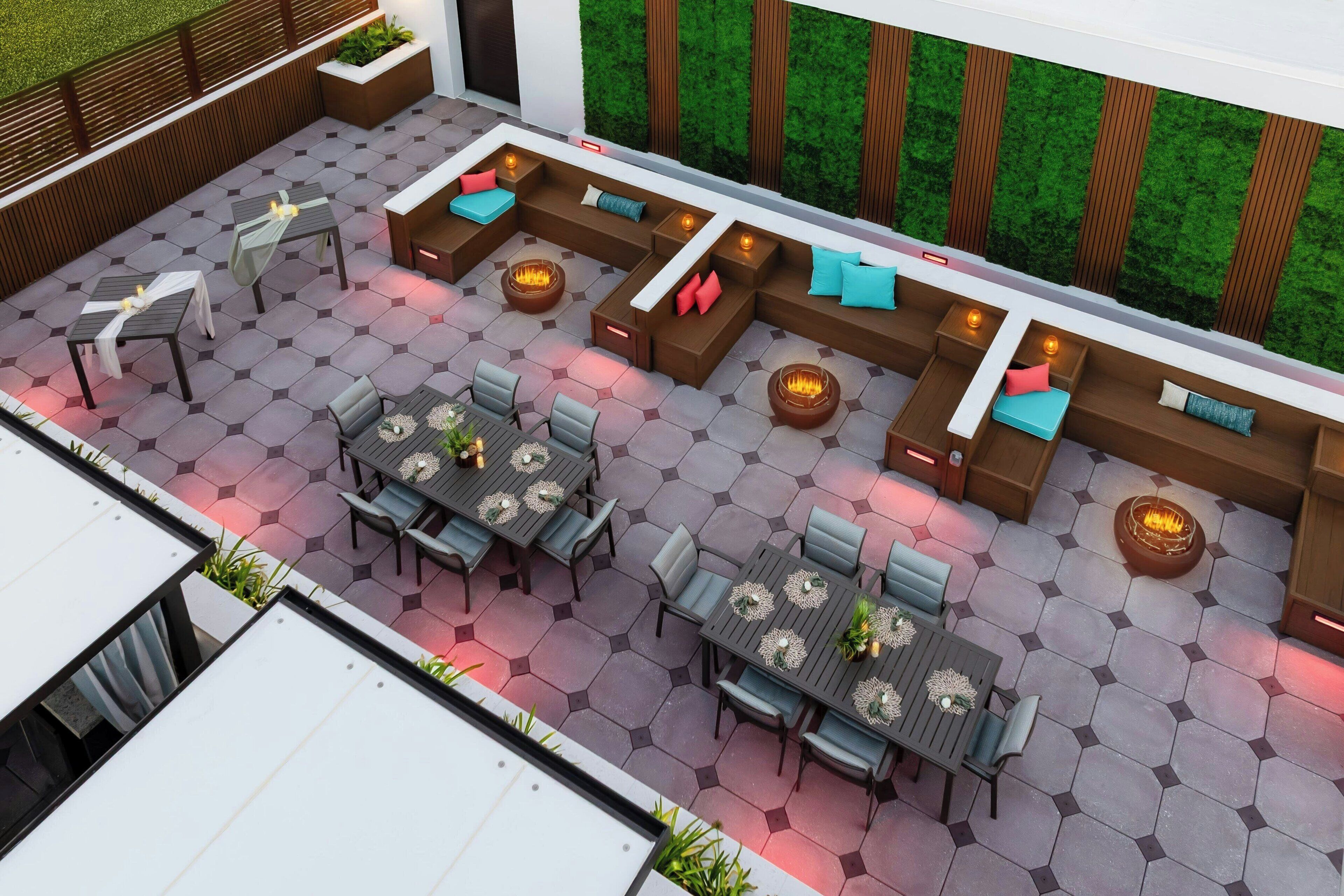 A modern outdoor patio with hexagonal tiles, seating areas, and fire pits.