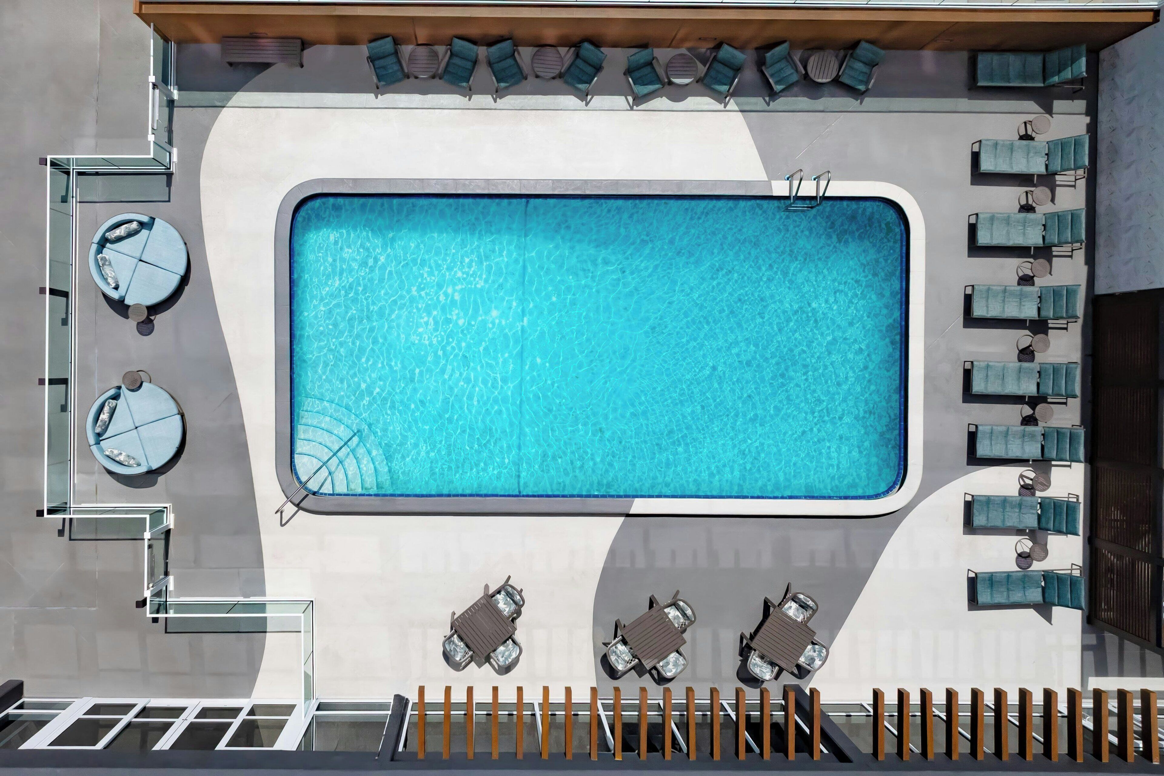 A rooftop swimming pool with a sun terrace, lounge chairs, and a glass balustrade.