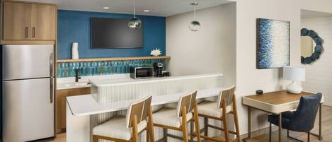 A modern kitchen with a central island, wooden cabinets, and a seating area with chairs.