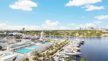 Un port de plaisance où sont amarrés des bateaux le long de la rive, une piscine et, en arrière-plan, une vue sur la ville.