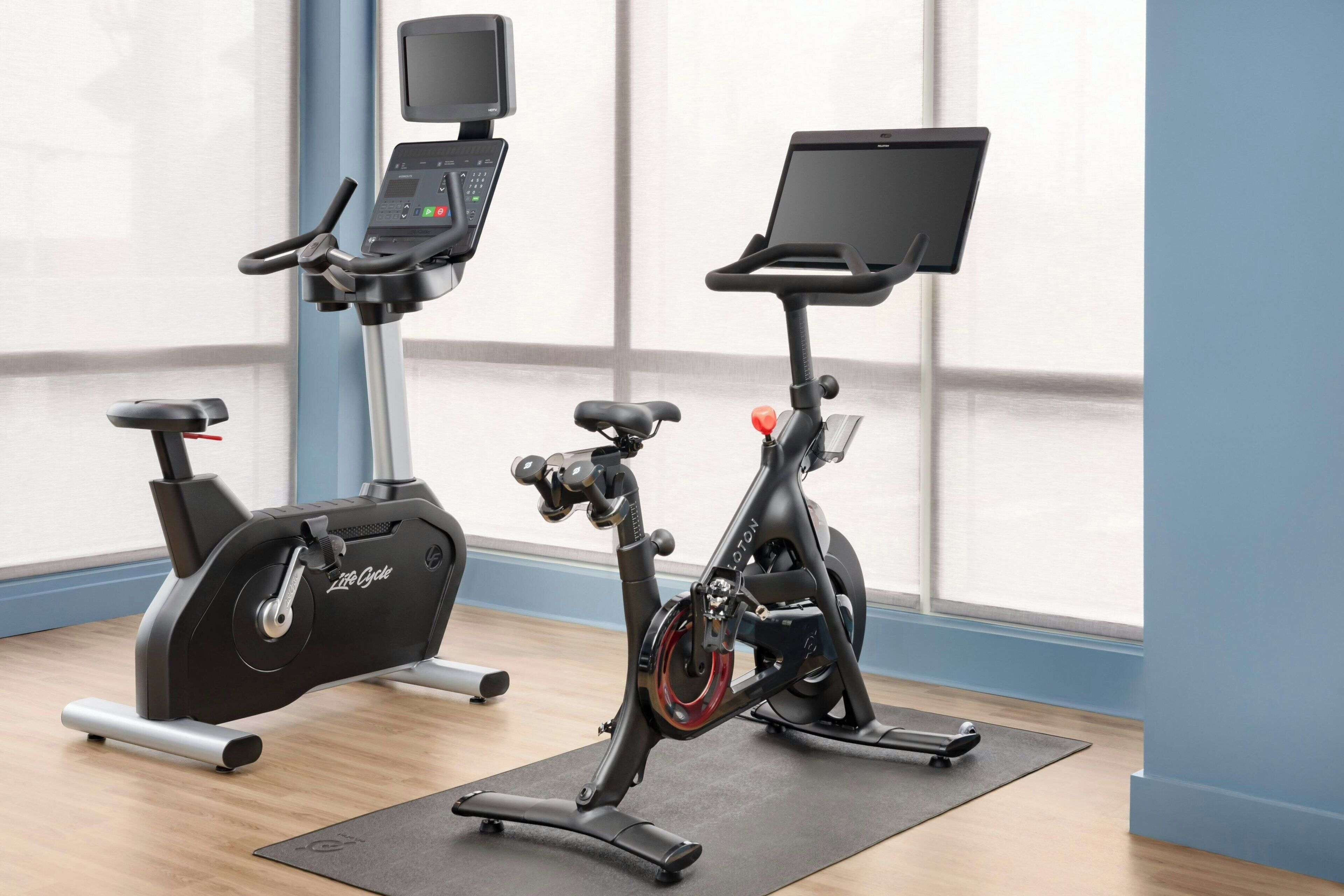 An indoor exercise area with two stationary bikes, one with a digital display and the other with a tablet.