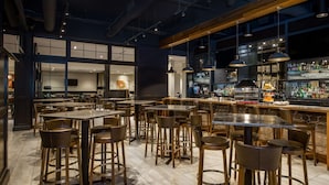 A modern bar area with multiple seating options, including bar stools and tables, and a well-stocked bar counter. - Sonesta Charlotte Lower South End (Charlotte)