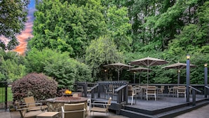 An outdoor patio area with seating, a fire pit, and umbrellas. - Sonesta Charlotte Lower South End (Charlotte)