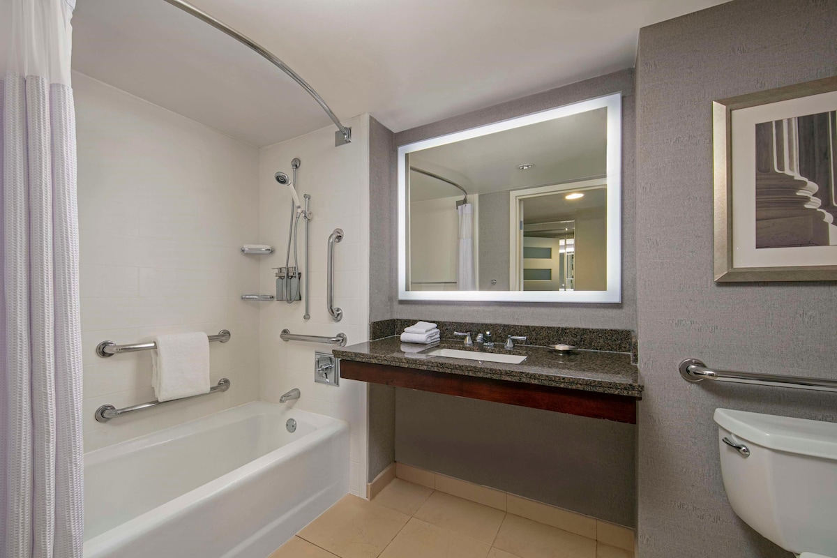 Een moderne badkamer met een bad, een wastafel met spiegel en een toilet.