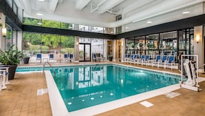 An indoor swimming pool with clear water, surrounded by blue chairs and exercise equipment. - Sonesta Charlotte Lower South End (Charlotte)