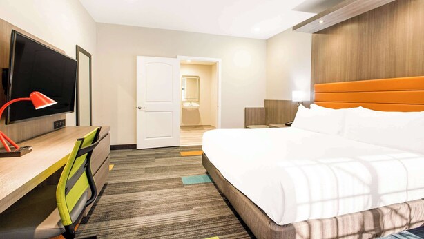 A hotel room with a bed, desk, TV, and a door leading to a bathroom. - Rodeway Inn near Melrose Ave (Los Angeles)