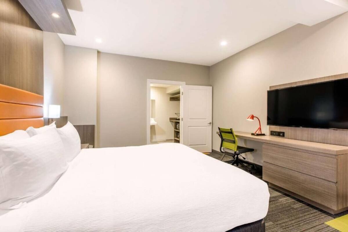A hotel room with a bed, a desk, a television, and a closet.