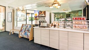 A reception area with a coffee machine, a juice dispenser, and a display of pastries. - Rodeway Inn near Melrose Ave (Los Angeles)