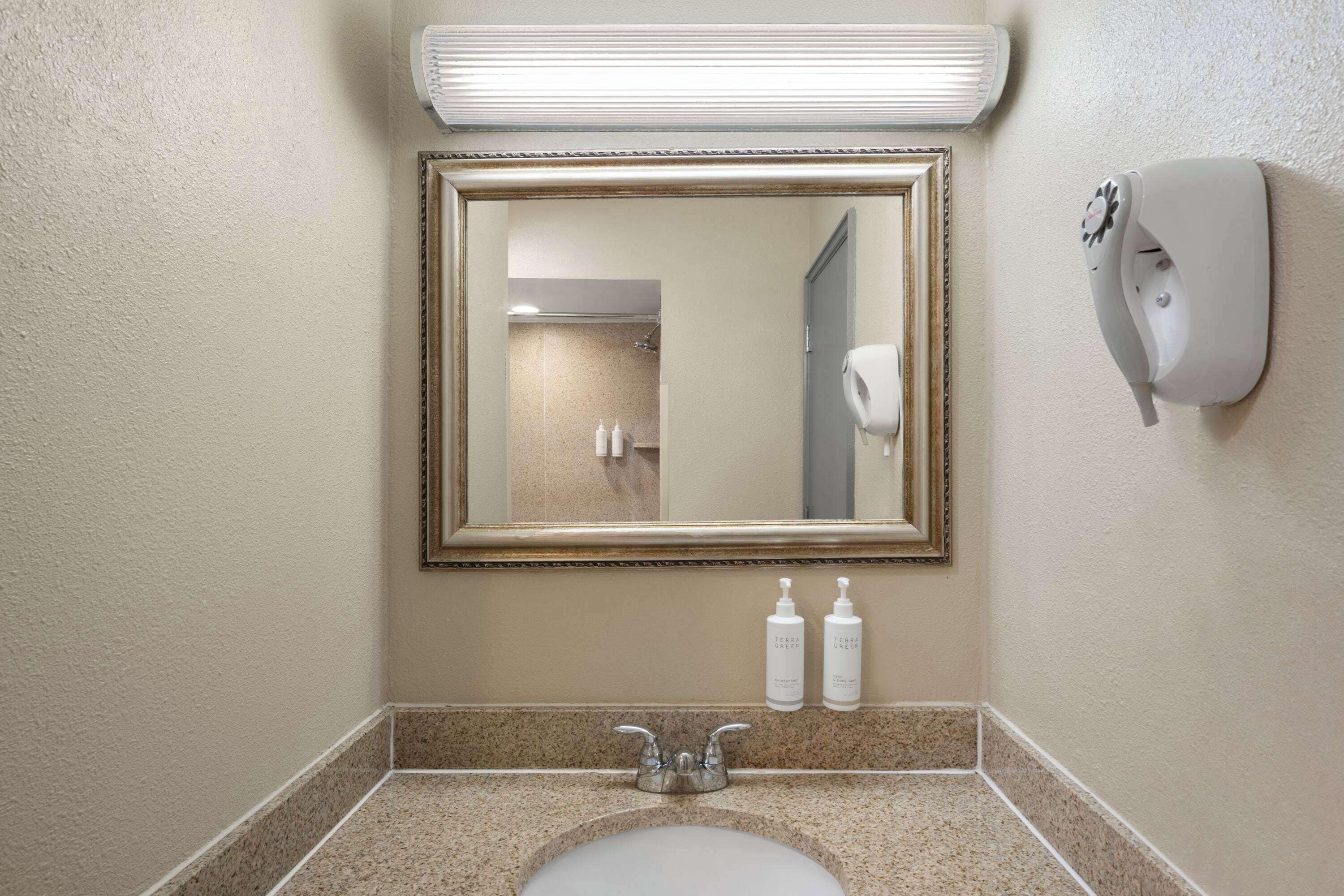 Un bagno con lavandino, specchio e asciugamani ad aria.