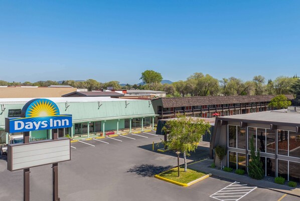 A Days Inn with a parking lot, a green building, and a modern structure with large windows.