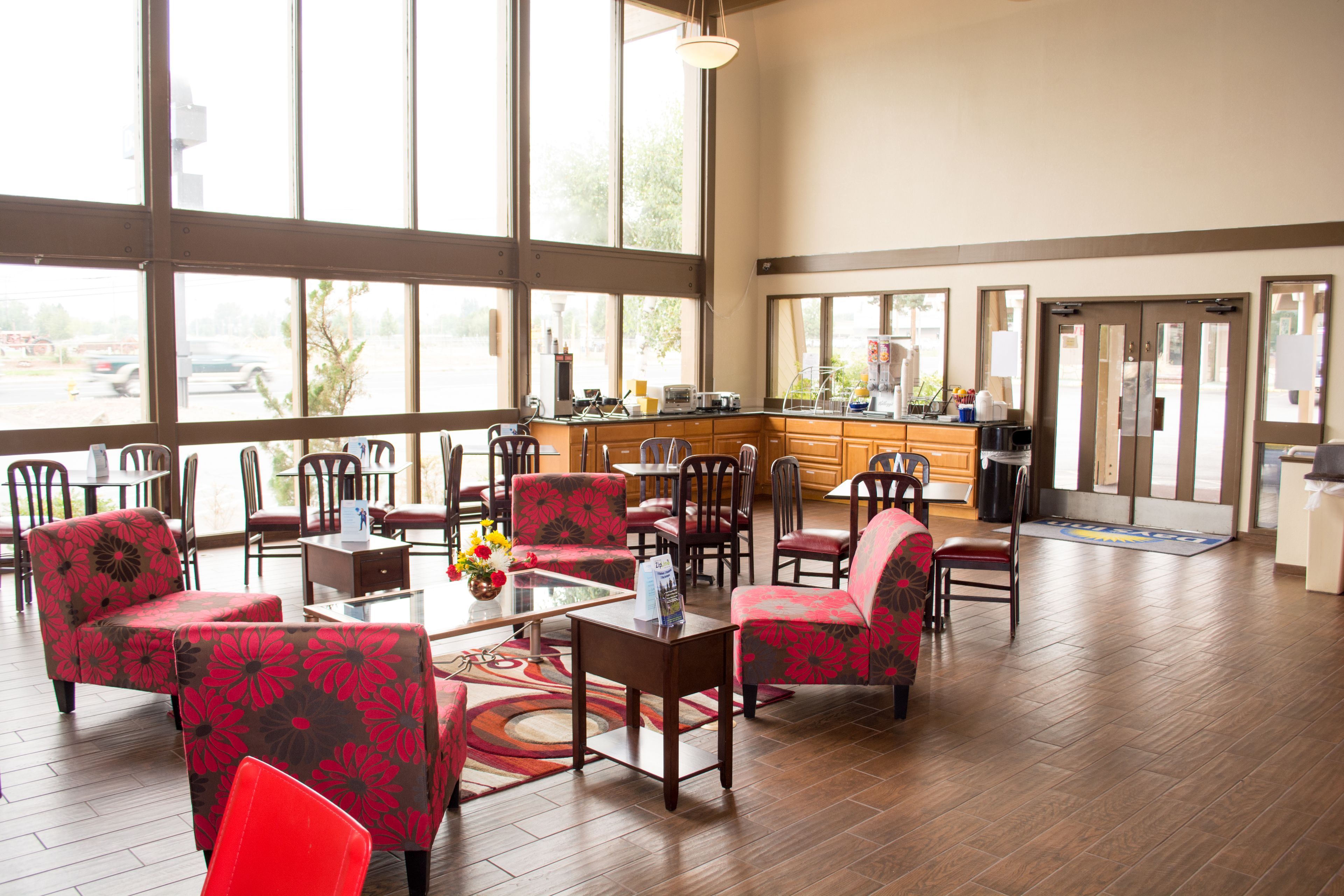A spacious lobby with large windows, multiple seating areas, and a kitchen counter.