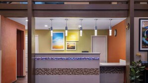 A reception area with a reception desk, overhead pendant lights, framed artwork, and a clock on the wall.