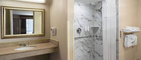 A bathroom with a sink, mirror, shower, and towel rack.