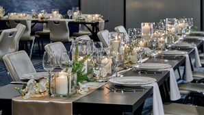 A long dining table set with candles, glassware, and white flowers, suggesting a formal dining experience. - Le Méridien St. Louis Clayton (St. Louis)
