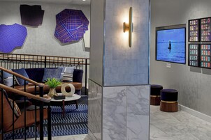 Un moderno salón con escalera, un televisor mostrando una vista al mar y un panel con fotografías.