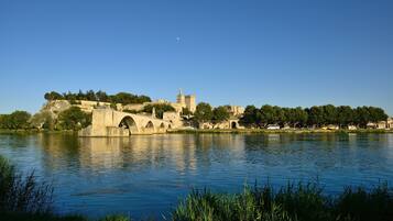 A historic stone bridge over a calm river, surrounded by lush greenery and ancient buildings.