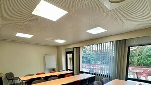 A conference room with multiple tables and chairs, a whiteboard, and large windows with a view of the outdoors. - ibis Avignon Centre Pont de l'Europe (Avignon)