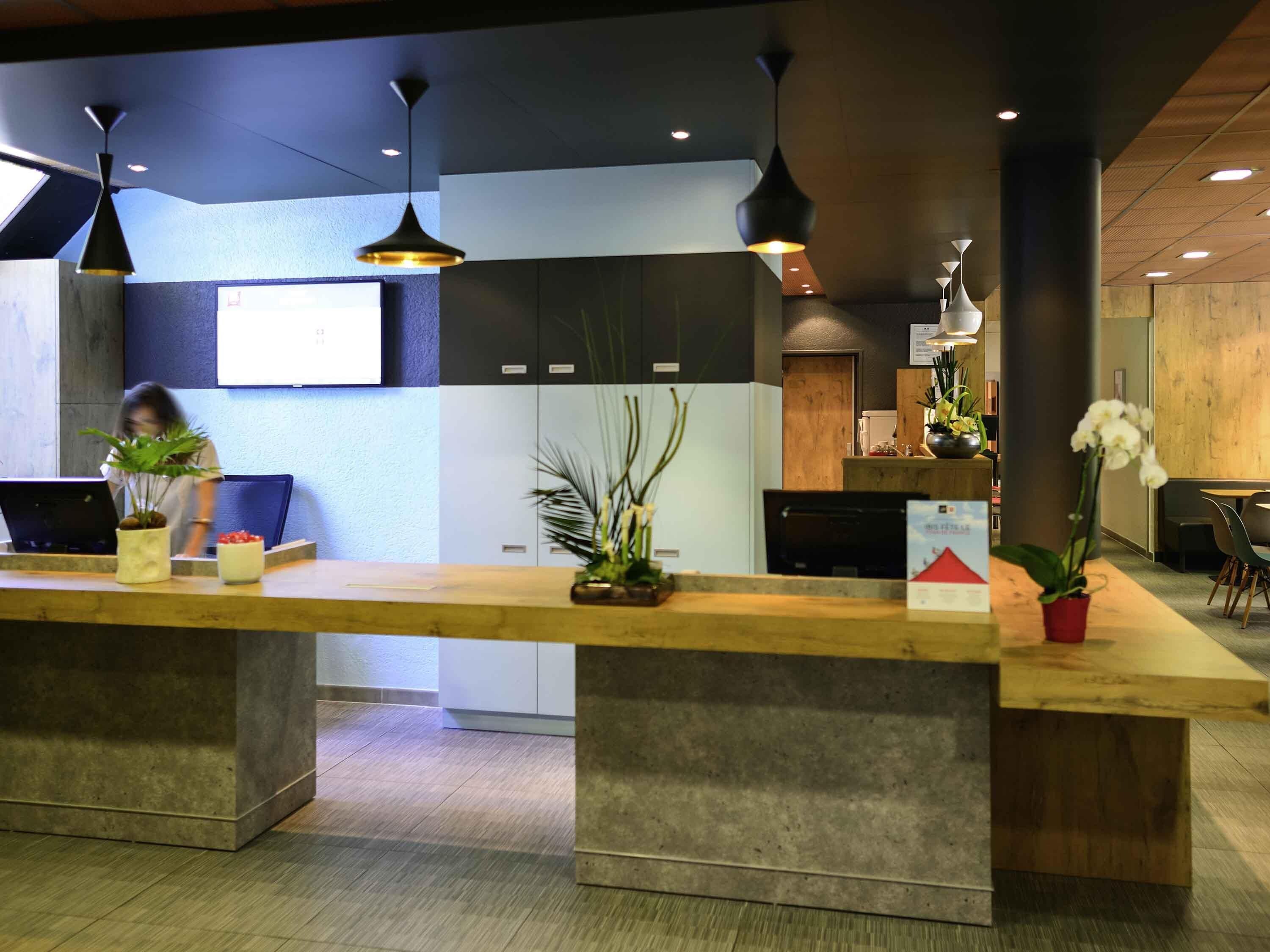 A reception desk with a wooden counter, potted plants, and a modern interior design.