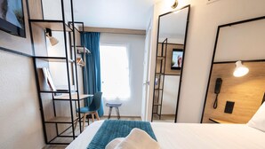 A hotel room with a bed, a desk, a chair, a wardrobe, and a mirror. - ibis Avignon Centre Pont de l'Europe (Avignon)