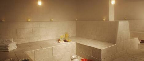 Une salle de spa équipée d’une grande baignoire, d’une petite table avec des serviettes et des articles de toilette, et d’un banc.