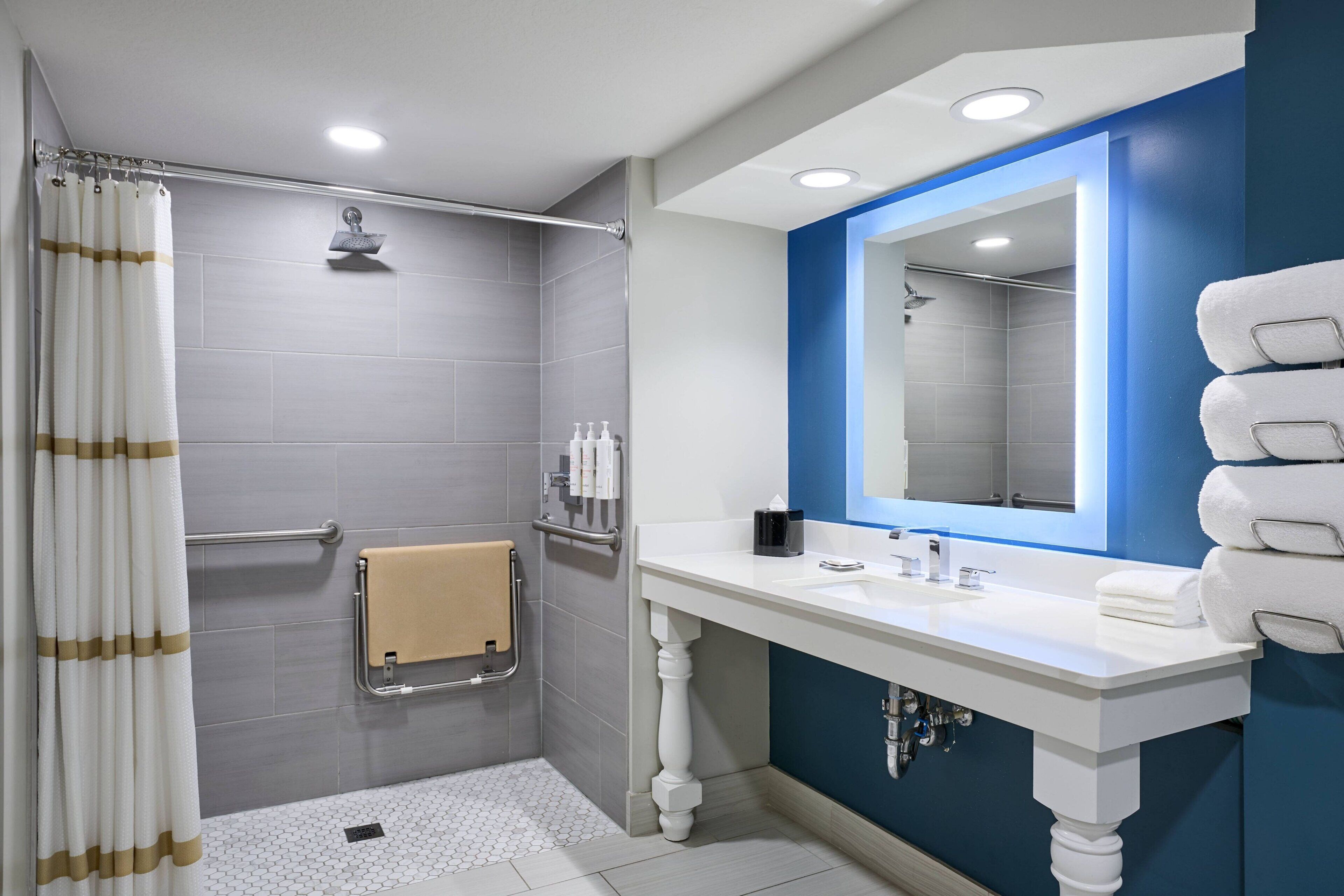 A modern bathroom with a shower, a sink, and a mirror.