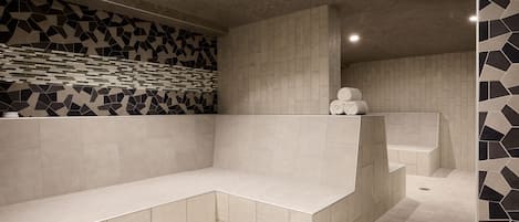 Une salle de bain moderne avec un revêtement mural géométrique en carreaux, un banc intégré et une baignoire.