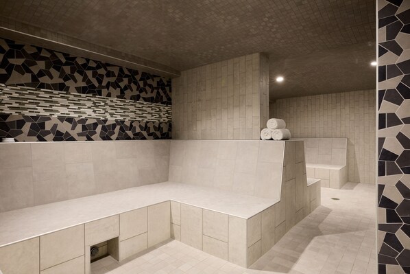 A modern bathroom with a geometric tile backsplash, a built-in bench, and a bathtub.