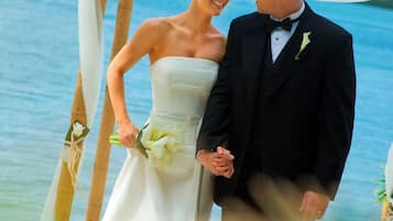 A couple standing under a canopy by a body of water.