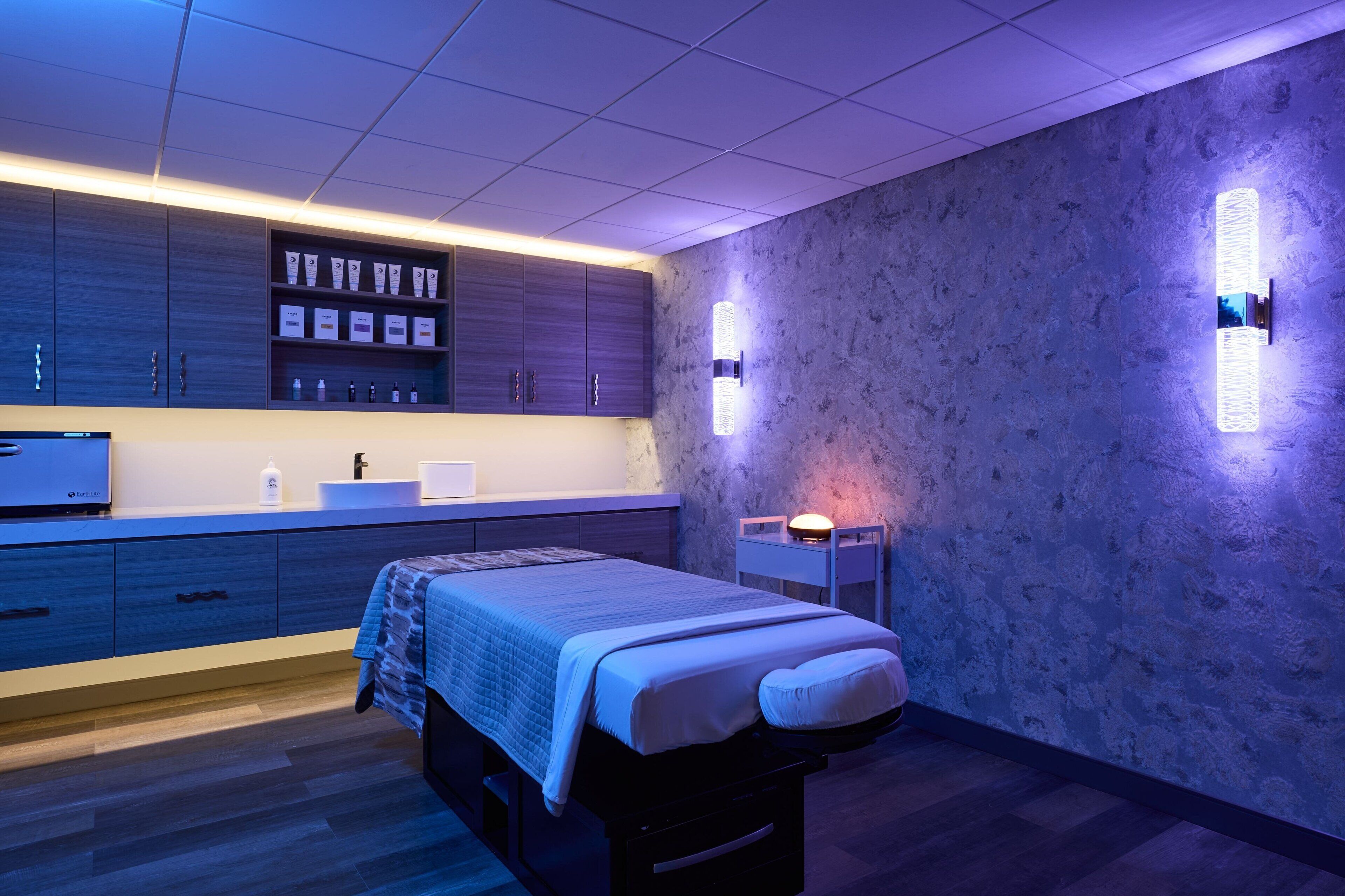 Une chambre moderne avec un lit, des tables de chevet et une étagère intégrée où sont rangés les articles de toilette.