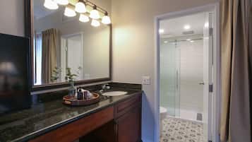 A bathroom with a large mirror, a sink, and a shower.