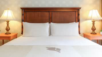 Un letto ben rifatto con una testiera in legno, due comodini con lampade e una parete decorata.