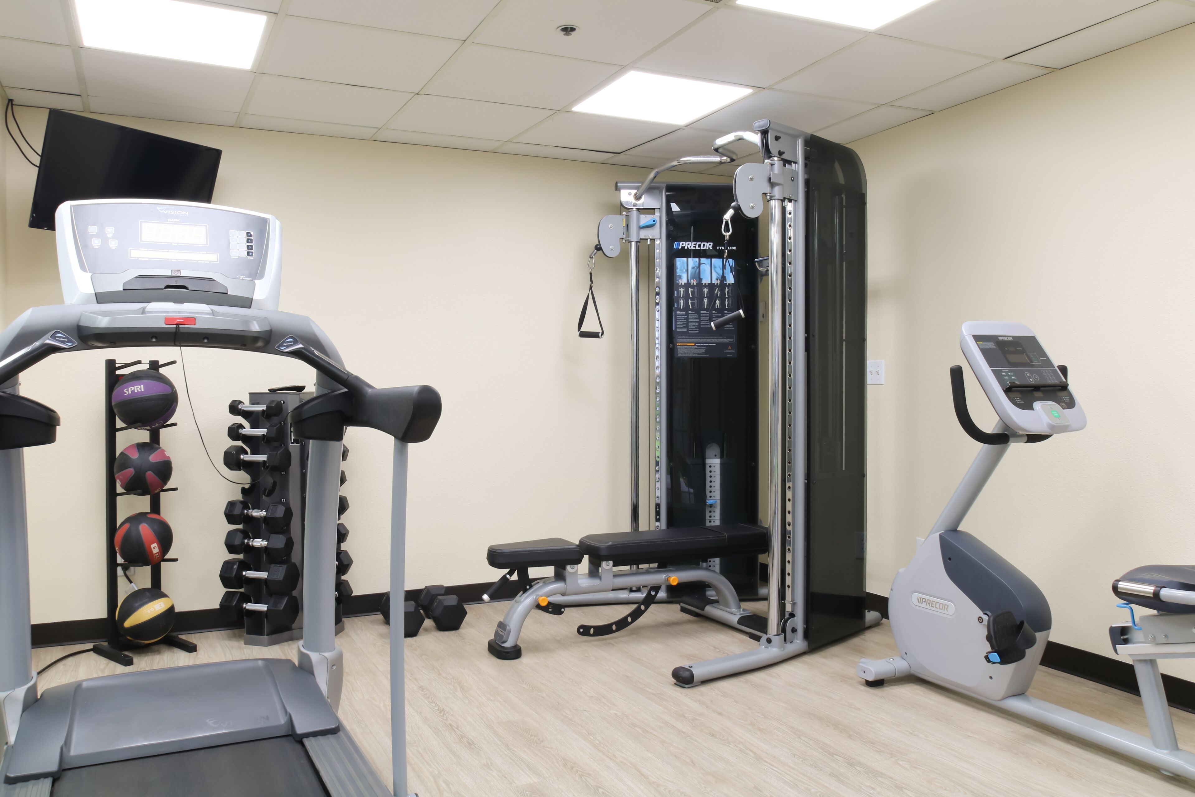 Un gimnasio con cinta de correr, elíptica, banco de pesas y diverso equipo de ejercicio.