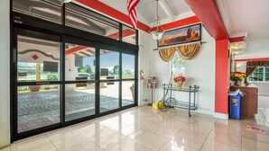 A hotel lobby with a large glass door, a reception desk, and a view of the outside.