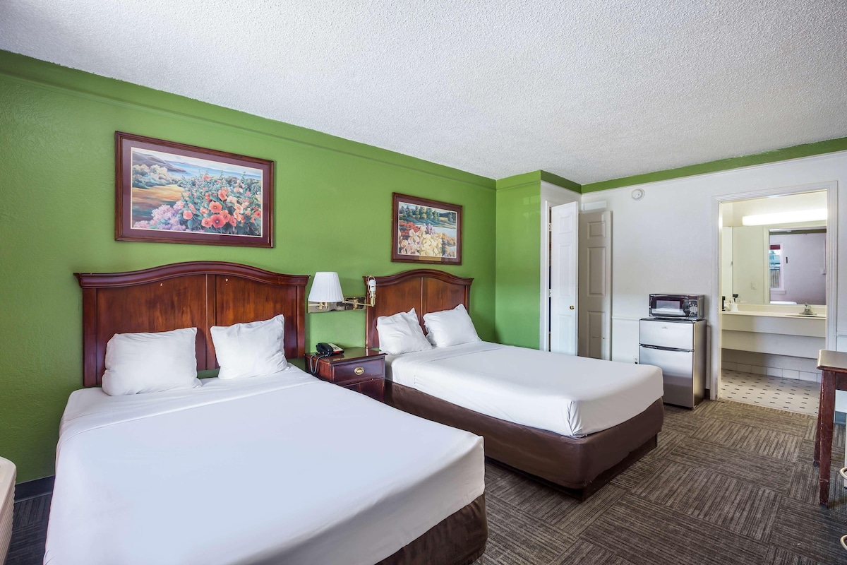 A hotel room with two beds, green walls, and a large mirror.