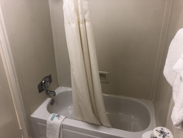A bathroom with a bathtub, a shower curtain, and a towel hanging on the wall.
