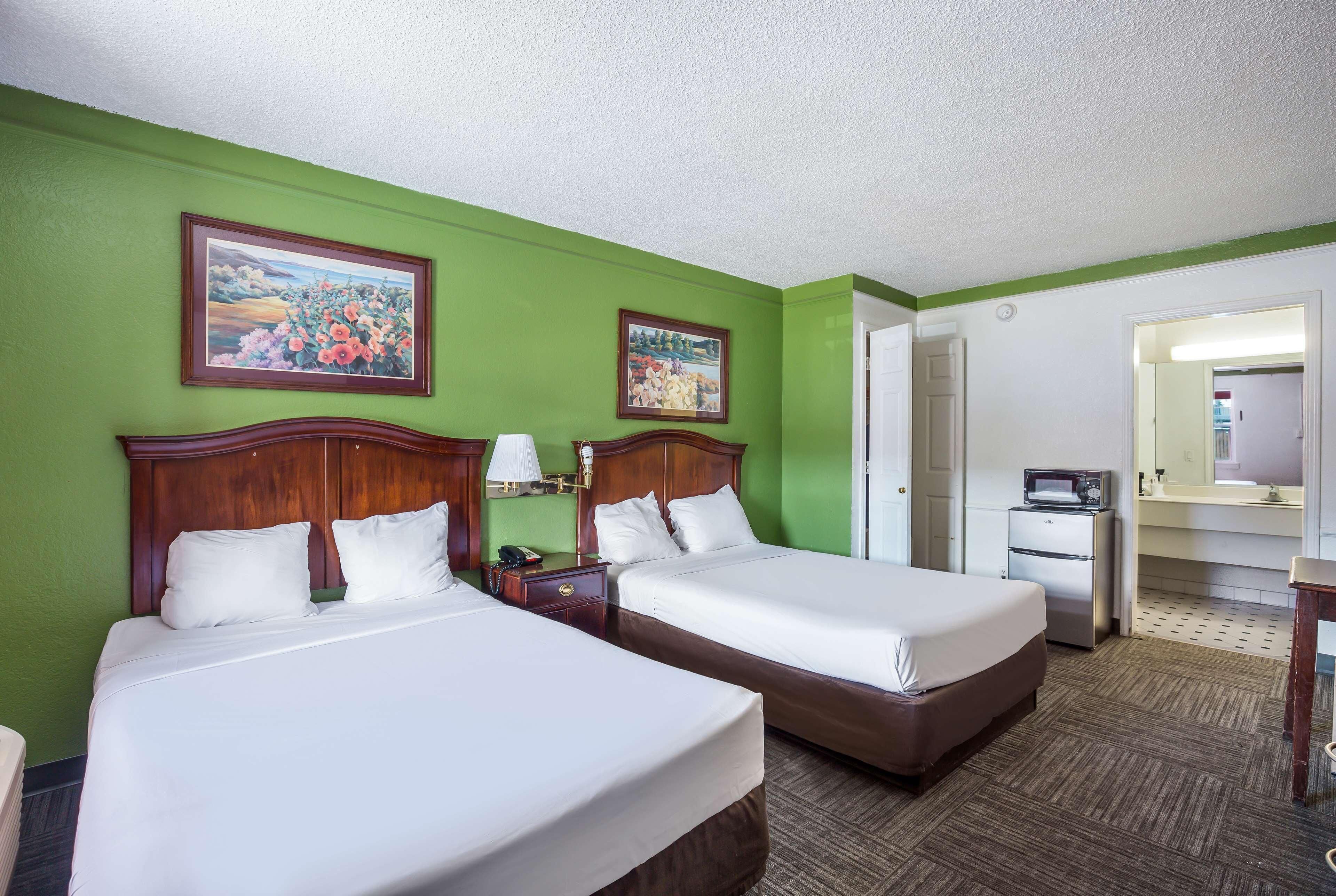 A hotel room with two beds, green walls, and a large mirror.