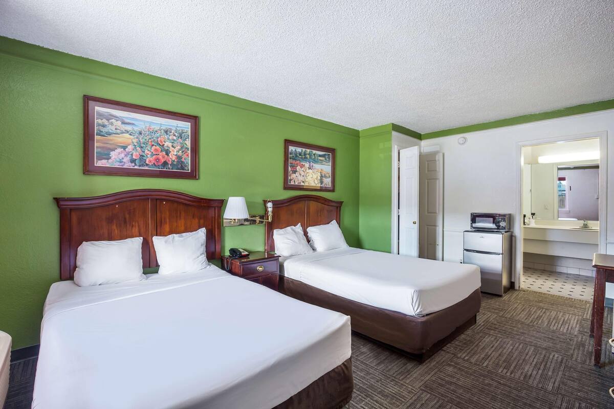 A hotel room with two beds, green walls, and a large mirror.