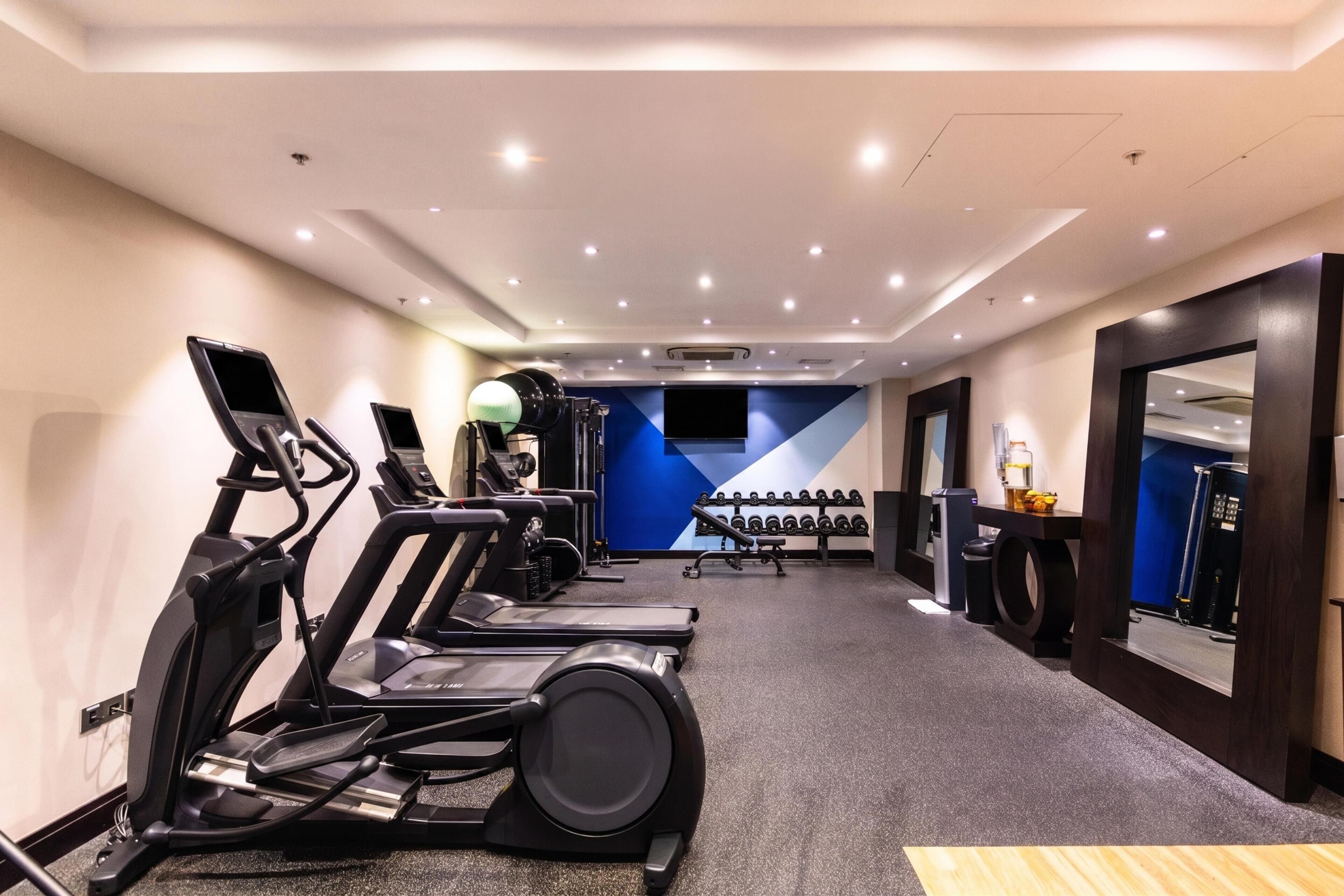 A gym with treadmills, weights, and a mirror.
