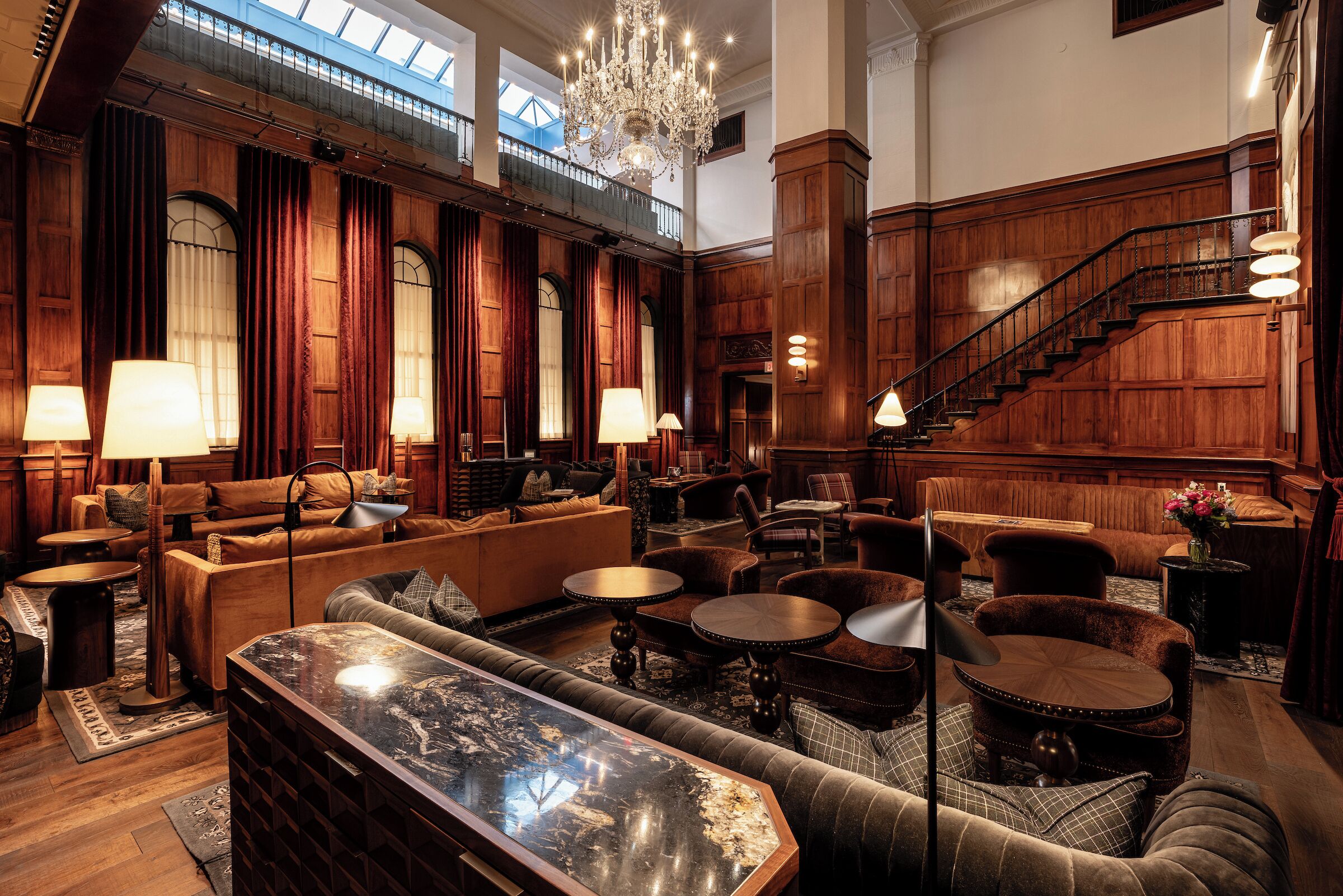 A spacious lobby with a high ceiling, a grand staircase, and multiple seating areas.