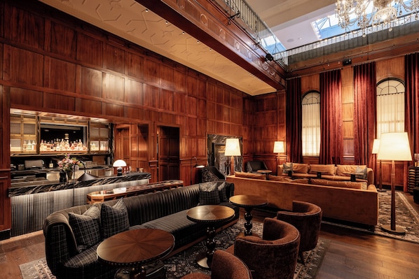 A spacious lobby with a bar area, seating arrangements, and a high ceiling with intricate wood paneling. - Heathman Hotel (Portland)