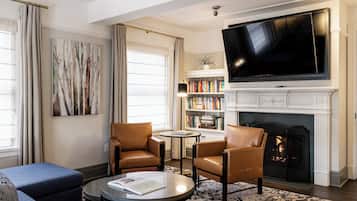 Un salon doté d’une cheminée, d’un grand téléviseur à écran plat, de fauteuils en cuir, d’une table basse et d’une bibliothèque.