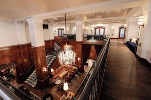 A grand lobby with a staircase, a chandelier, a seating area, and a bar.