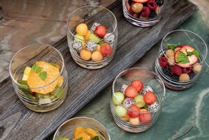 Una mesa de madera con cinco recipientes de vidrio con frutas variadas.